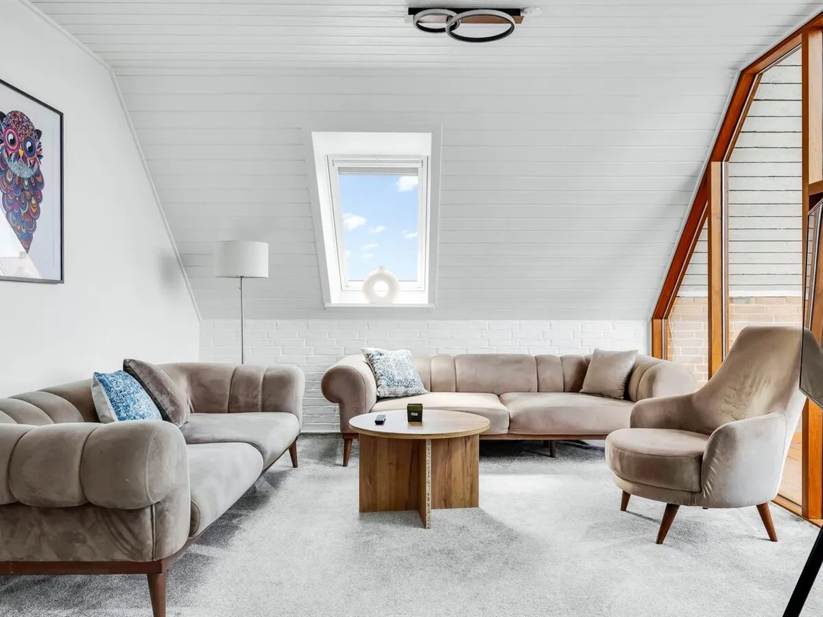 Stuen med to sofaer, lænestol og ovenlysvindue