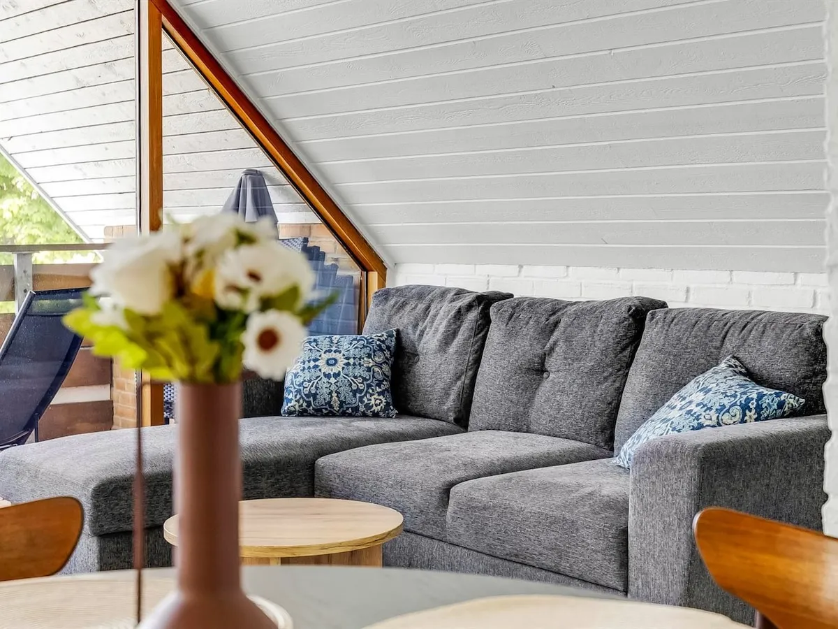Grå hjørnesofa med blå puder ved panoramavinduet