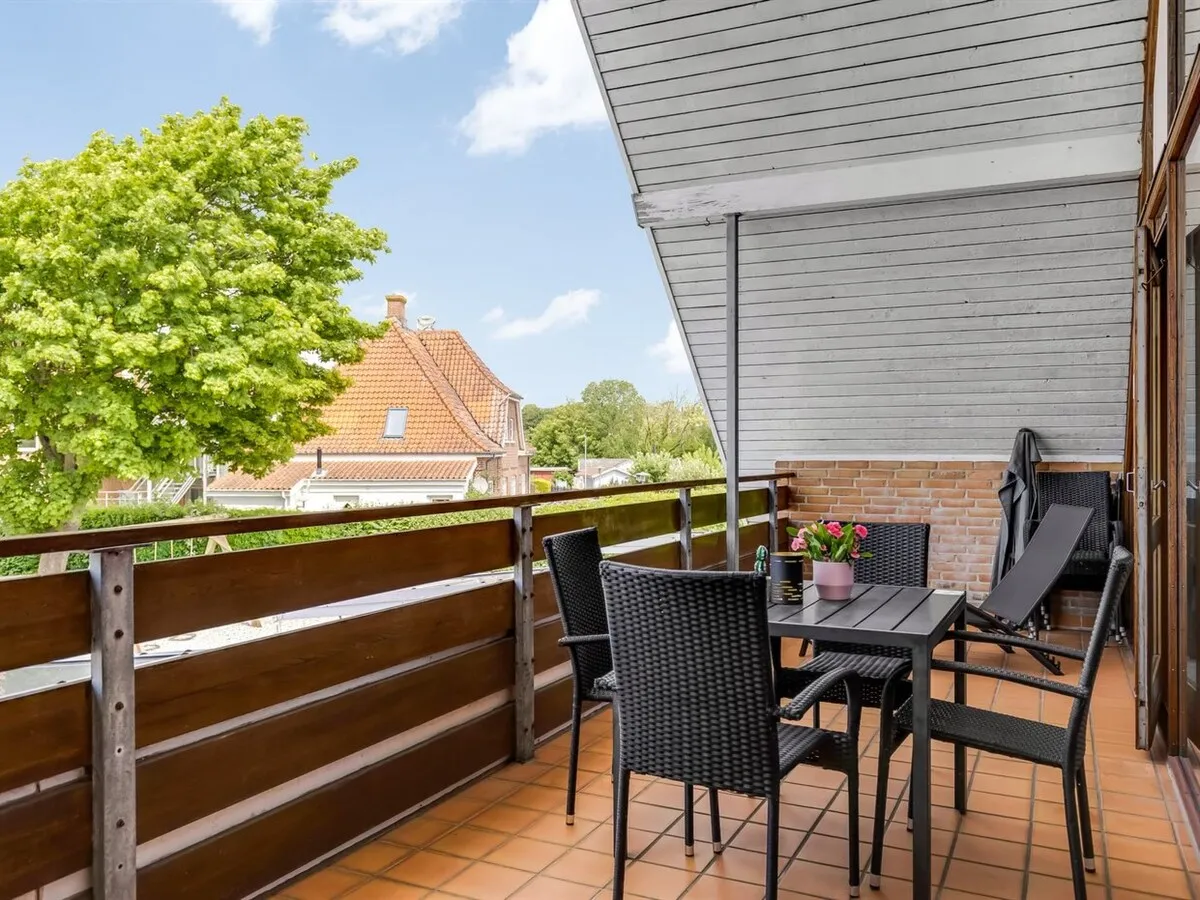 Overdækket balkon med spisebord og stole
