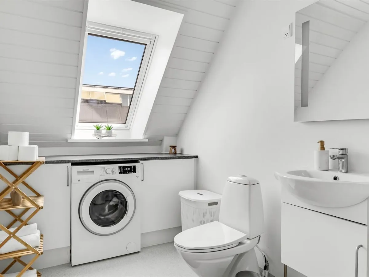 Badeværelset med vaskemaskine, toilet og håndvask